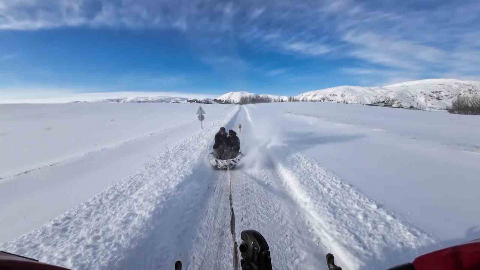 Kar yağışını fırsata çevirdiler, traktörün arkasında kayarak eğlendiler
