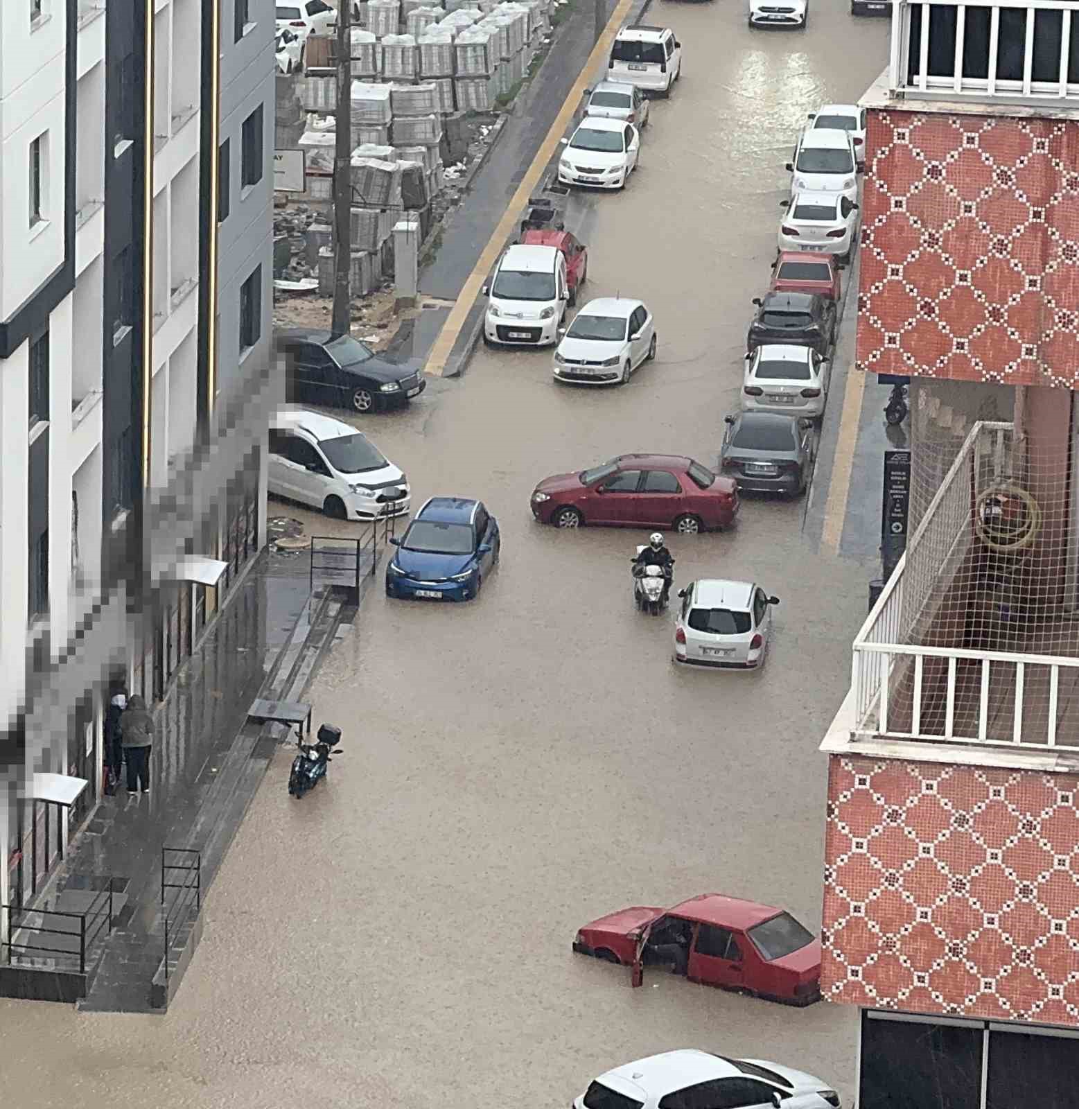 Yağmurda mahsur kalan motosikletli çareyi otomobilin üzerine çıkmakta buldu
